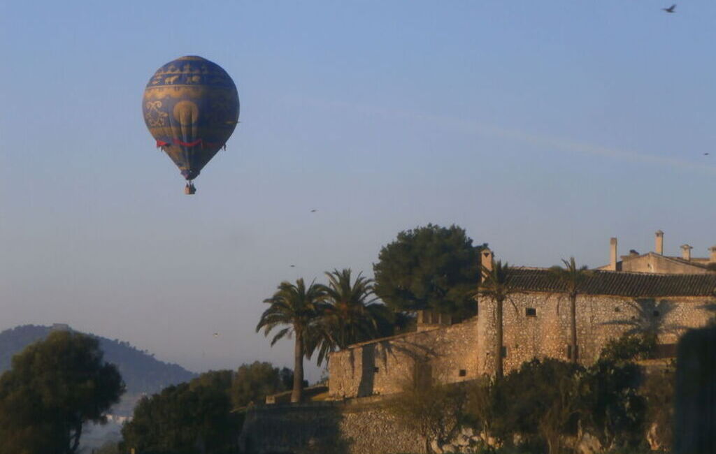 Balon lecący obok budynku, lot balonem na Majorce