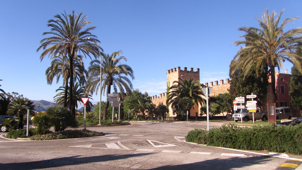 Widok na palmy i jedną z bram prowadzących do miasta Alcudia, Majorka